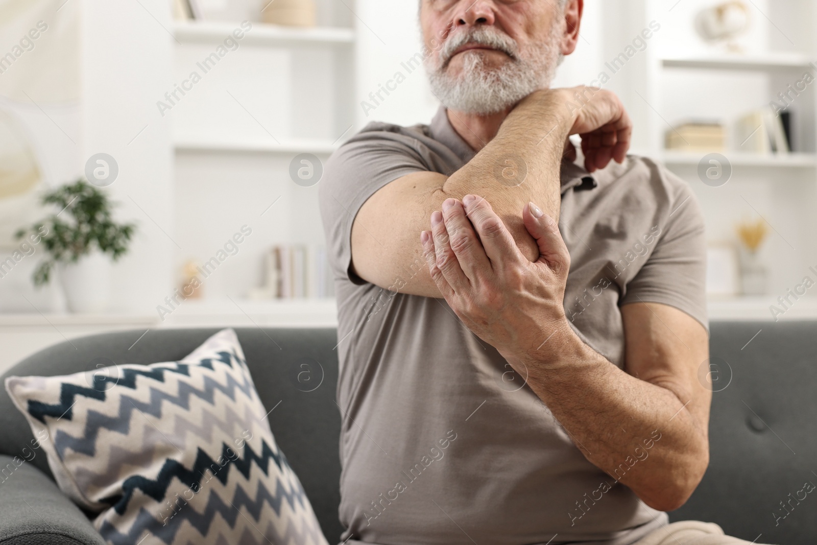 Photo of Arthritis symptoms. Man suffering from pain in elbow at home