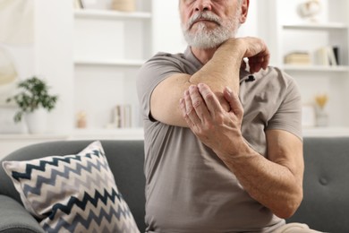 Arthritis symptoms. Man suffering from pain in elbow at home