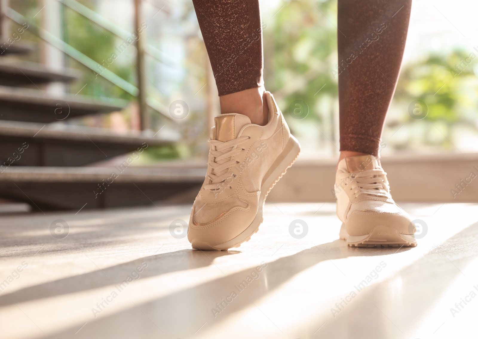 Photo of Young woman wearing stylish sneakers indoors, closeup