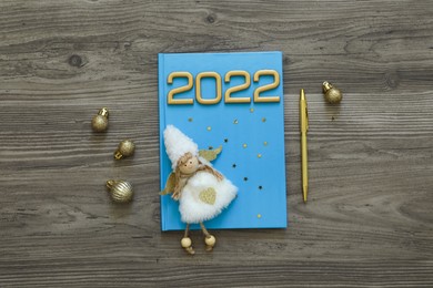 Photo of Planner and Christmas decor on wooden background, flat lay. 2022 New Year aims