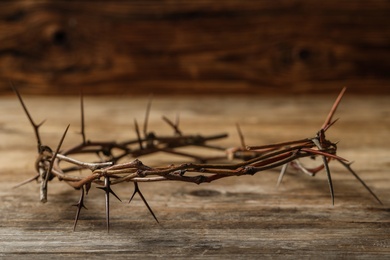 Photo of Crown of thorns on wooden table, space for text. Easter attribute