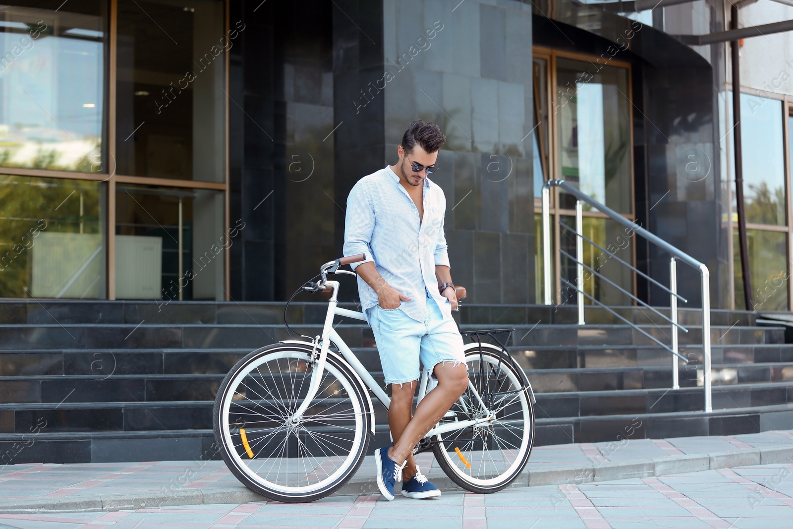 Photo of Handsome young hipster man with bicycle outdoors