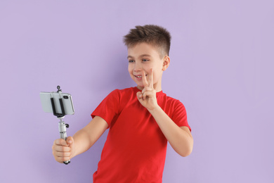 Photo of Cute little blogger recording video on violet background