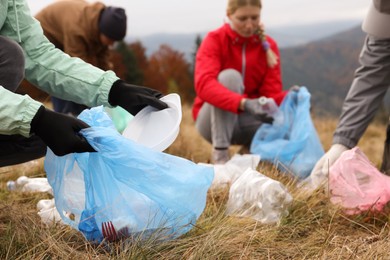 Photo of People with trash bags collecting garbage in nature