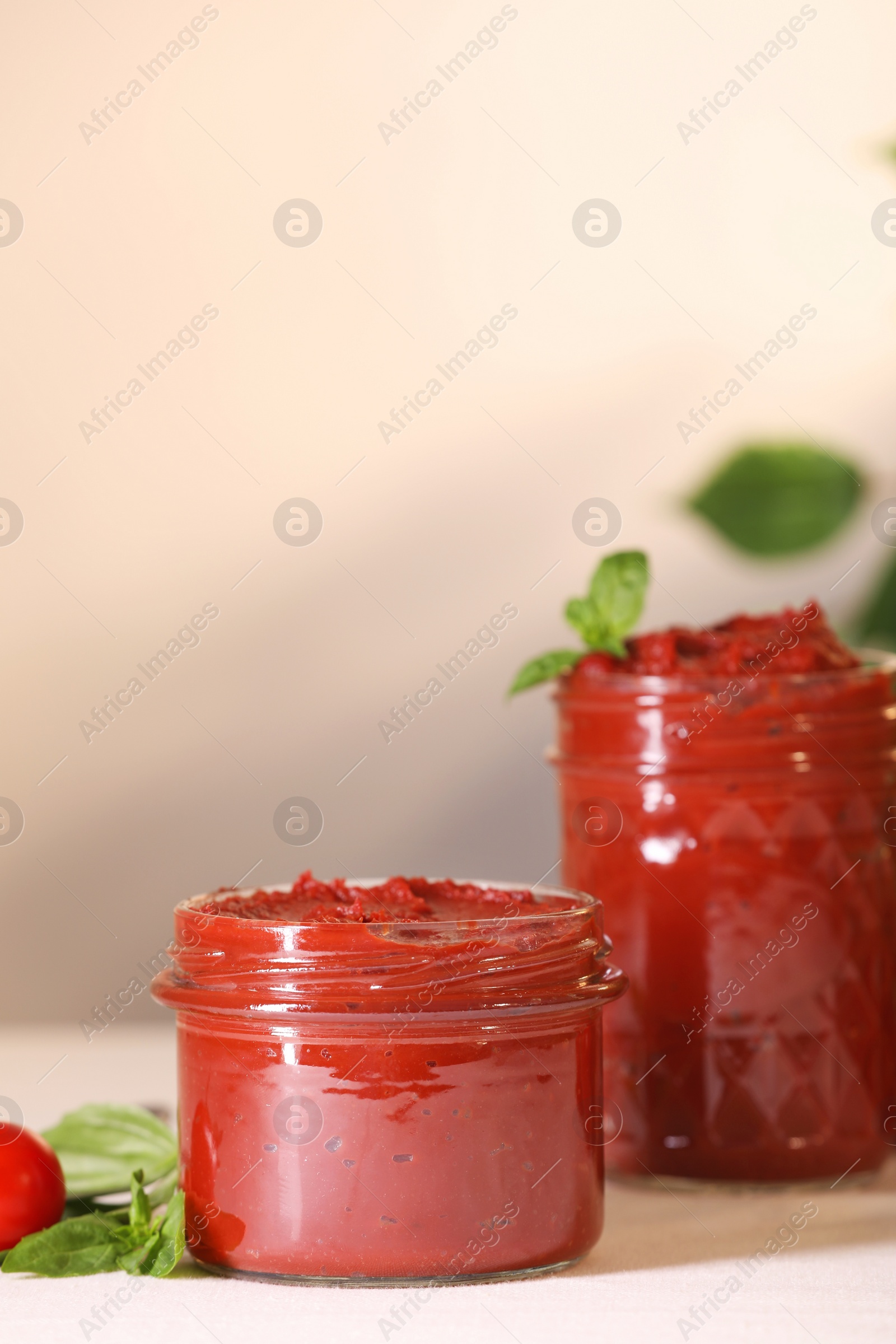 Photo of Jars of tasty tomato paste and ingredients on white table