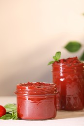 Photo of Jars of tasty tomato paste and ingredients on white table