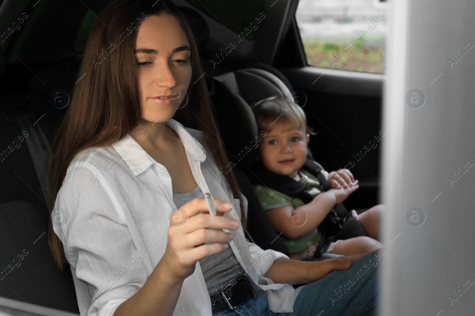 Photo of Mother with cigarette and child in car. Don't smoke near kids