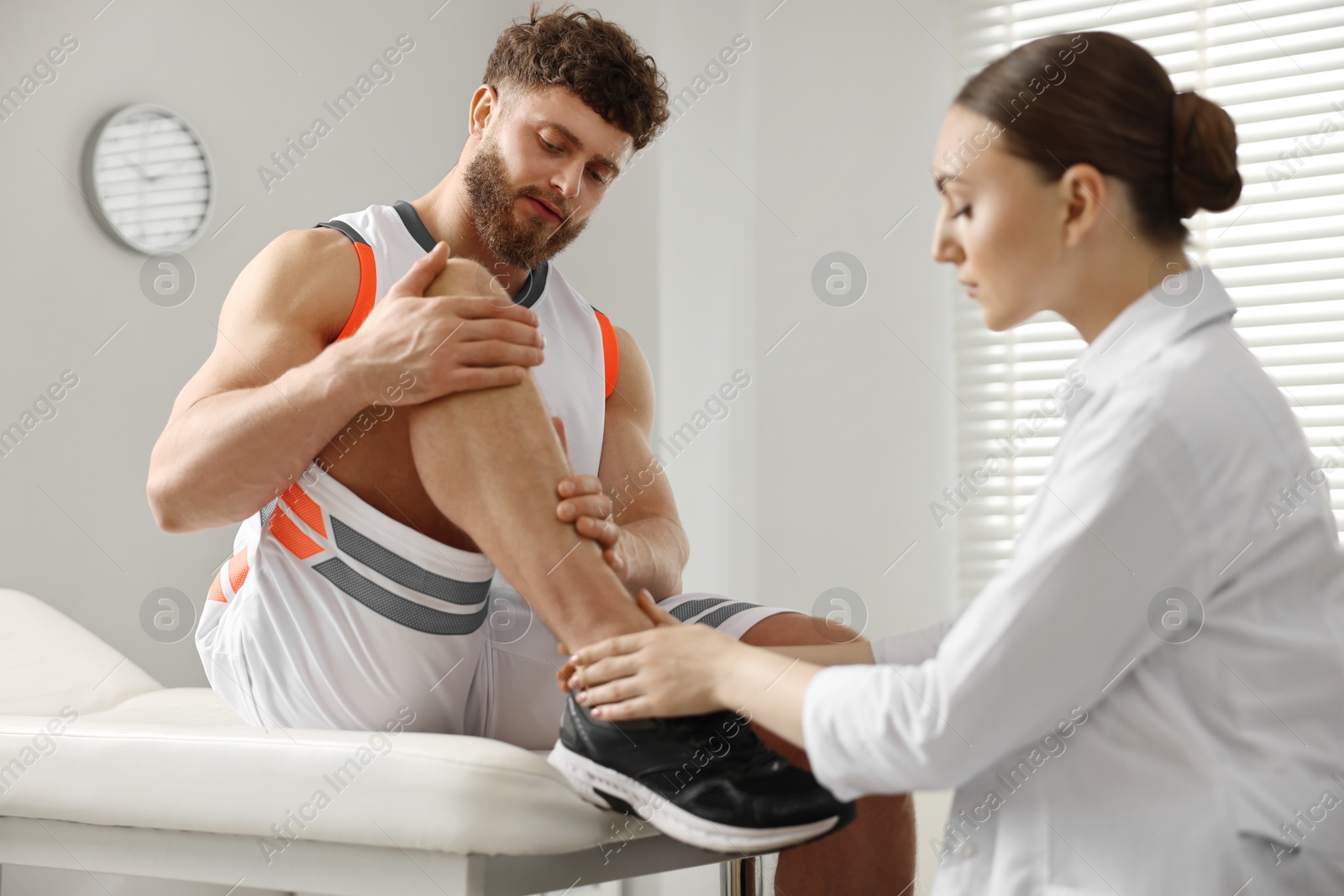 Photo of Sports injury. Doctor examining patient's leg in hospital