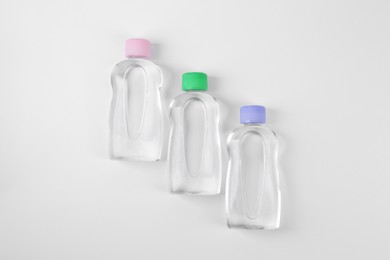 Photo of Transparent bottles with baby oil on white background, flat lay