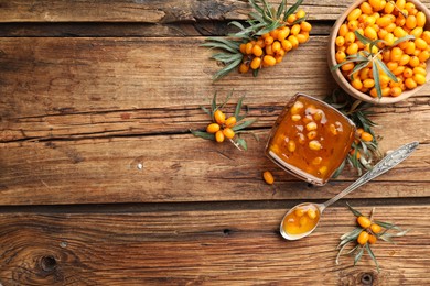 Photo of Delicious sea buckthorn jam and fresh berries on wooden table, flat lay. Space for text