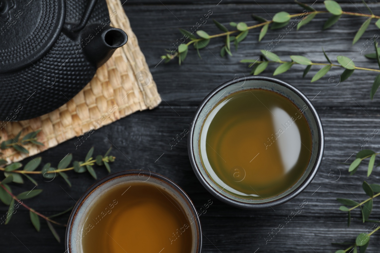 Photo of Aromatic eucalyptus tea on black wooden table, flat lay