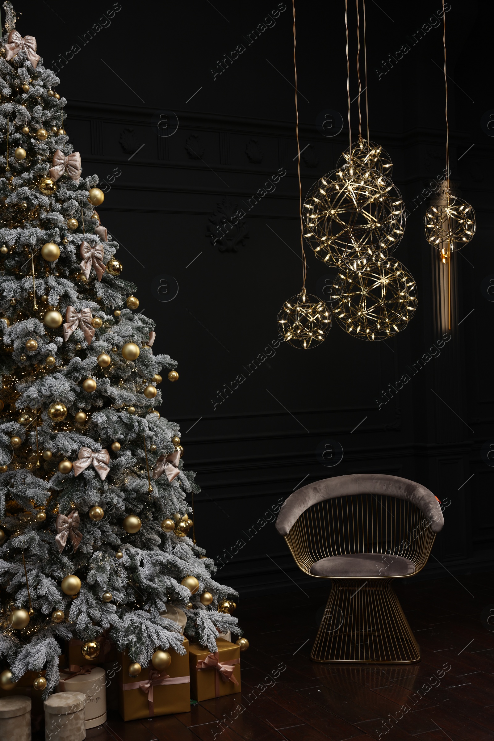 Photo of Beautiful decorated Christmas tree, chair and festive decor in dark room. Interior design