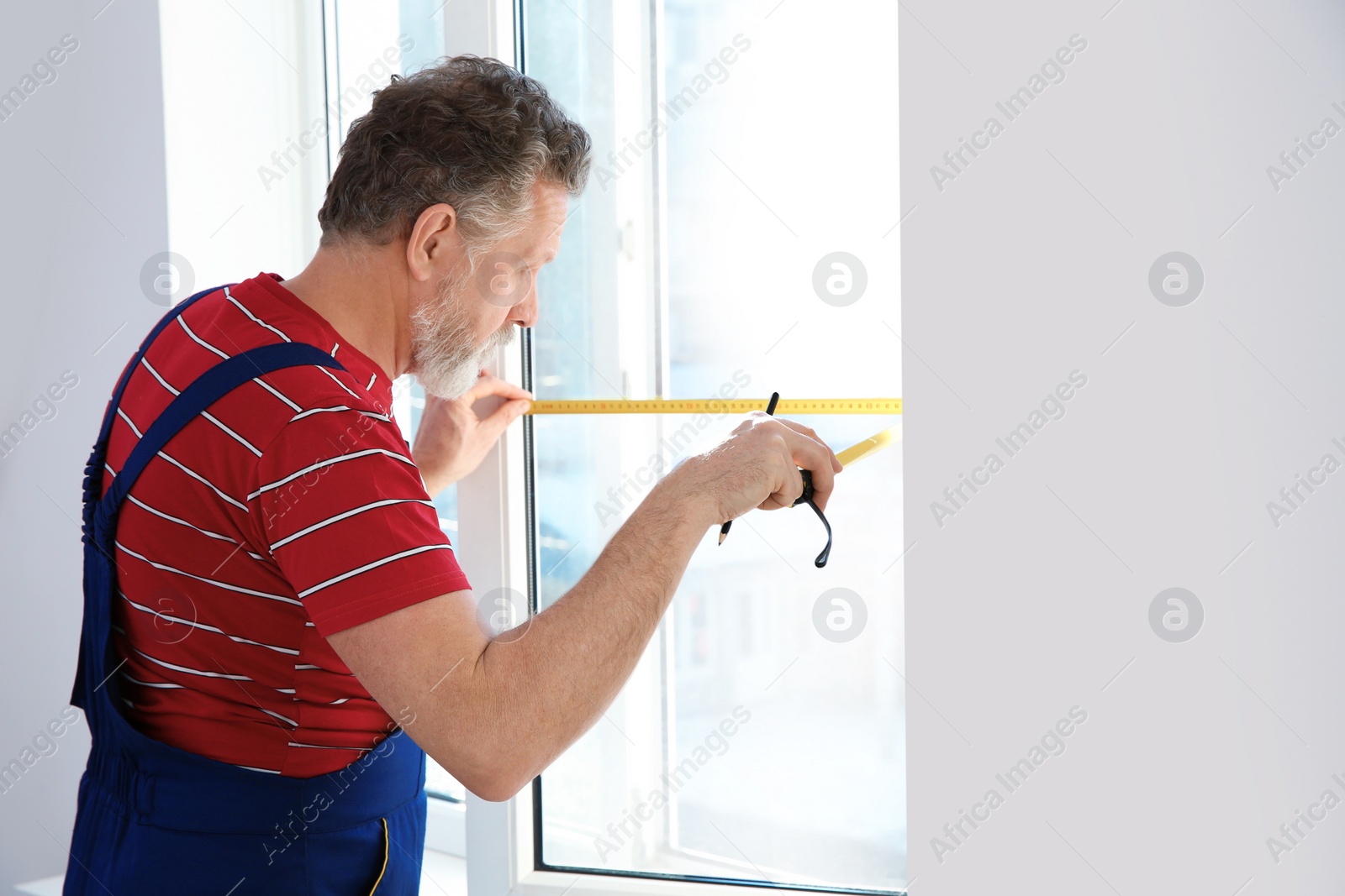 Photo of Service man measuring window for installation indoors