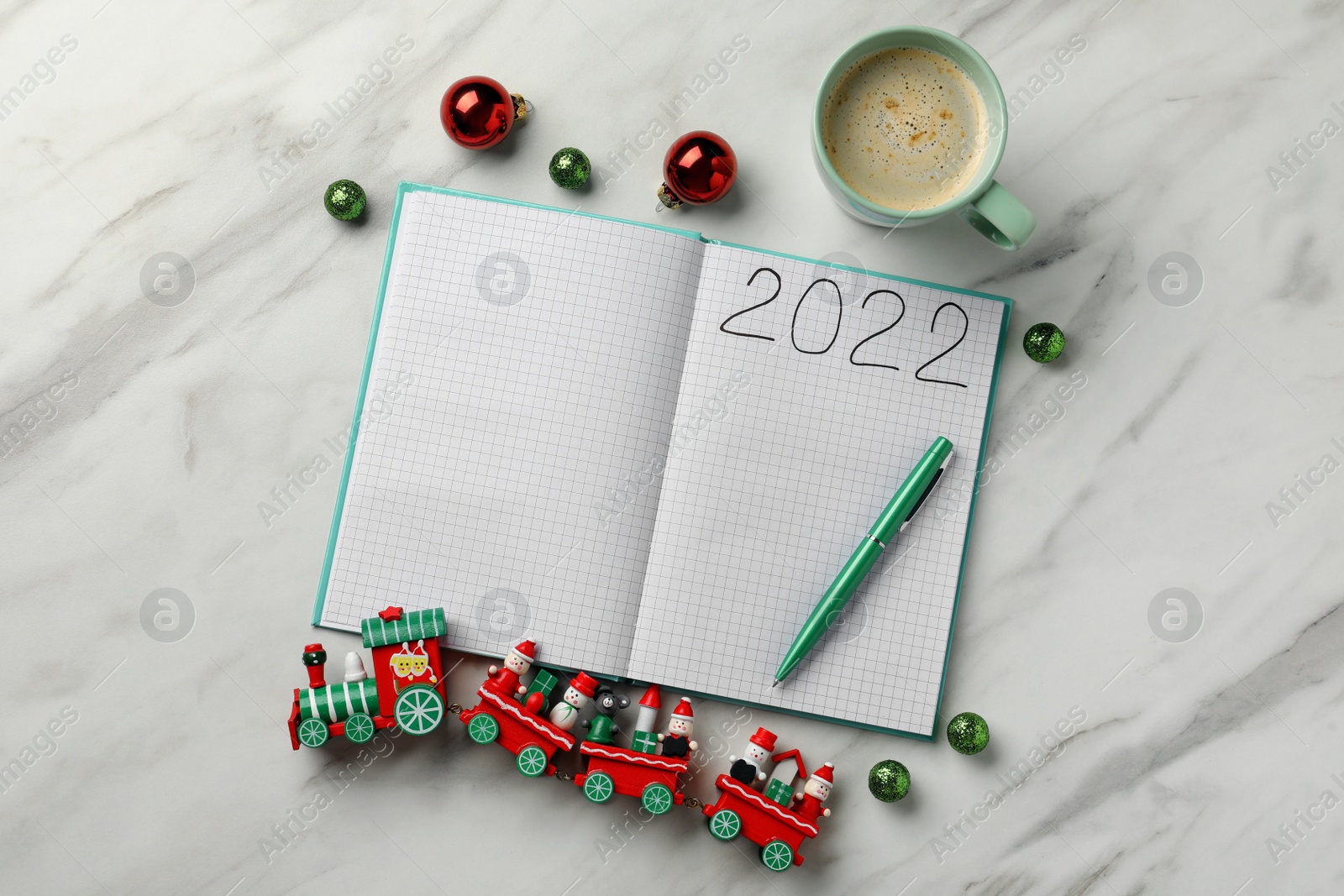 Photo of Open planner, cup of coffee and Christmas decor on white marble background, flat lay. 2022 New Year aims