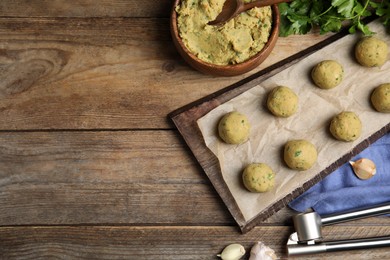 Photo of Raw falafel balls and ingredients on wooden table, flat lay. Space for text