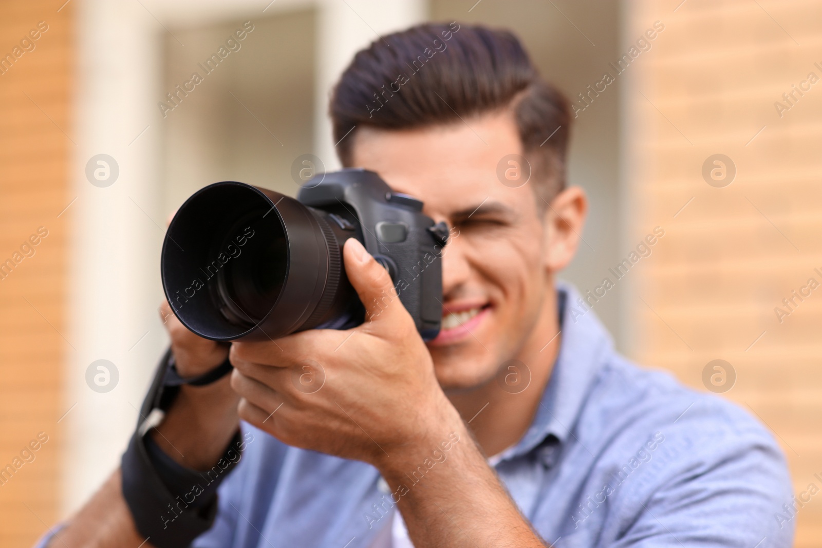 Photo of Photographer taking picture with professional camera outdoors, focus on device