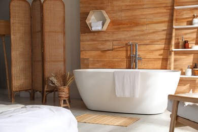 Photo of White tub and decor near wooden wall in room. Interior design