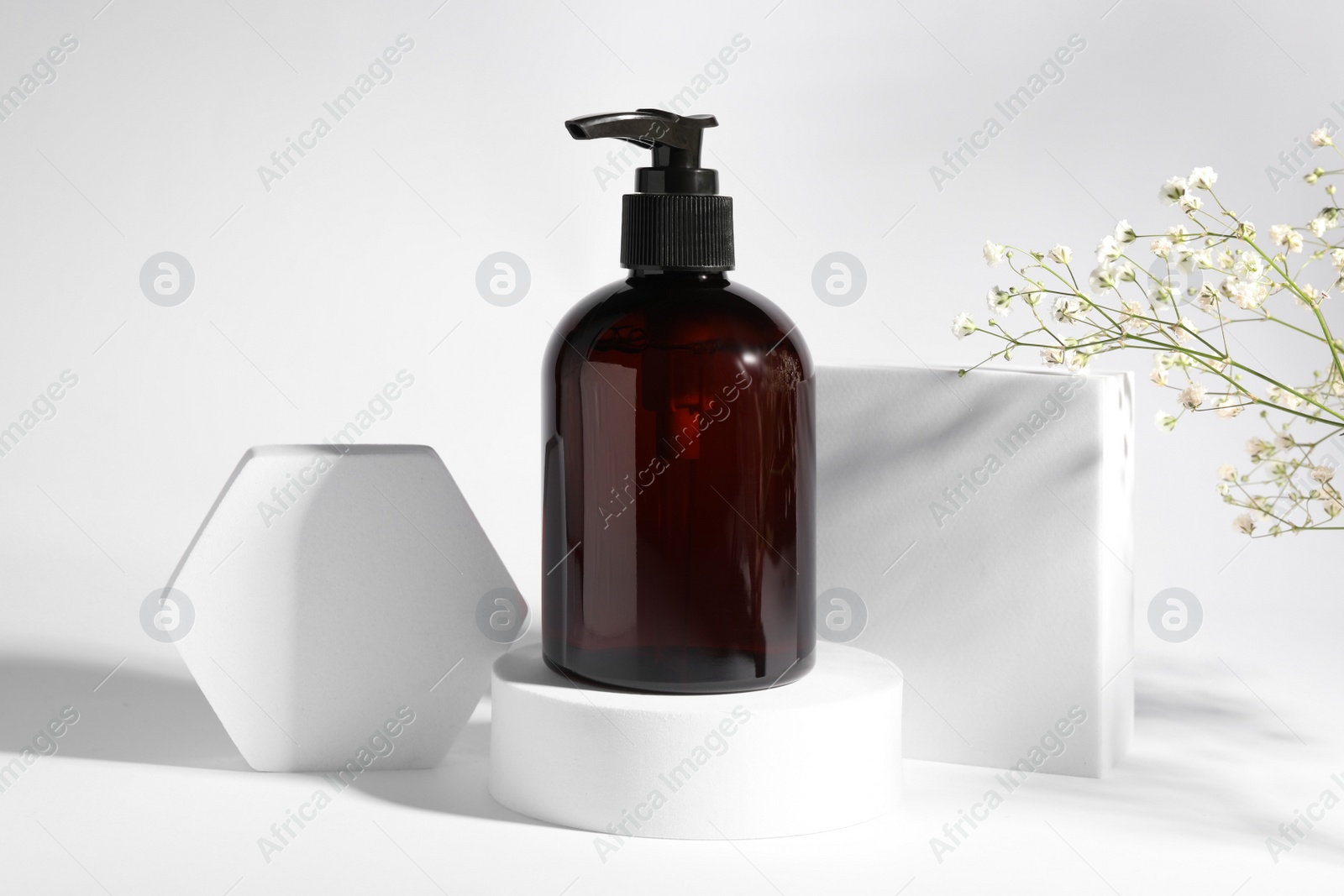 Photo of Bottle of shampoo and flowers on white background