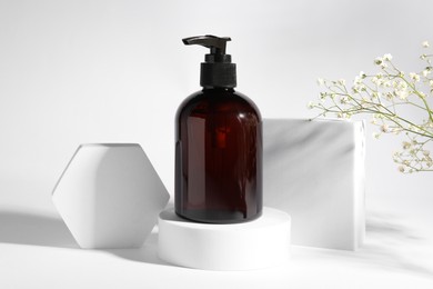 Photo of Bottle of shampoo and flowers on white background