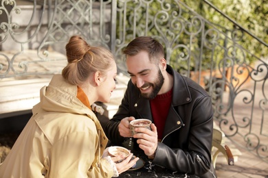 Photo of Lovely young couple enjoying tasty coffee at table outdoors