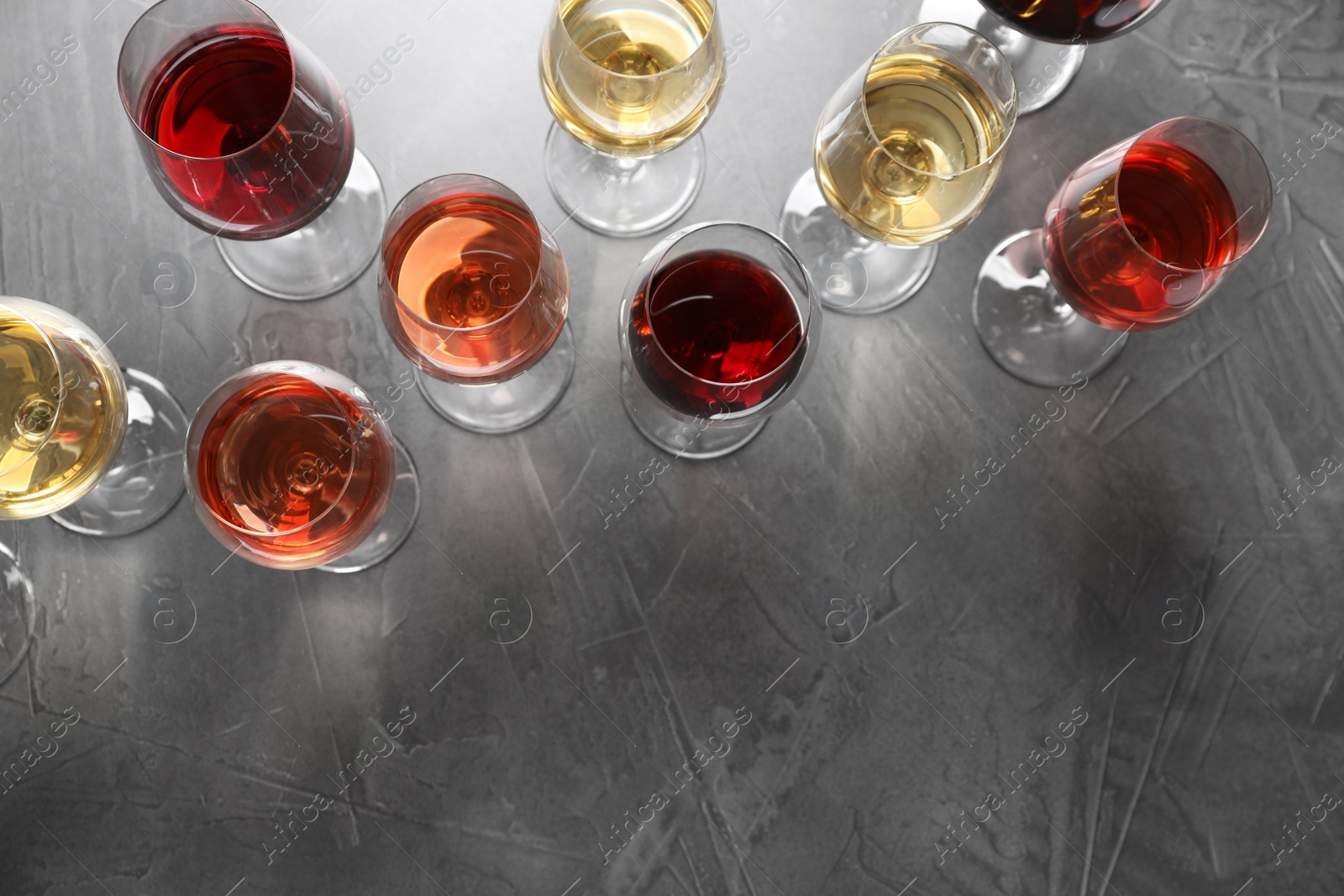 Photo of Different glasses with wine on grey background, flat lay. space for text