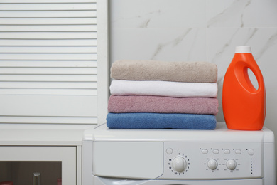 Stack of fresh towels and detergent on washing machine in laundry room