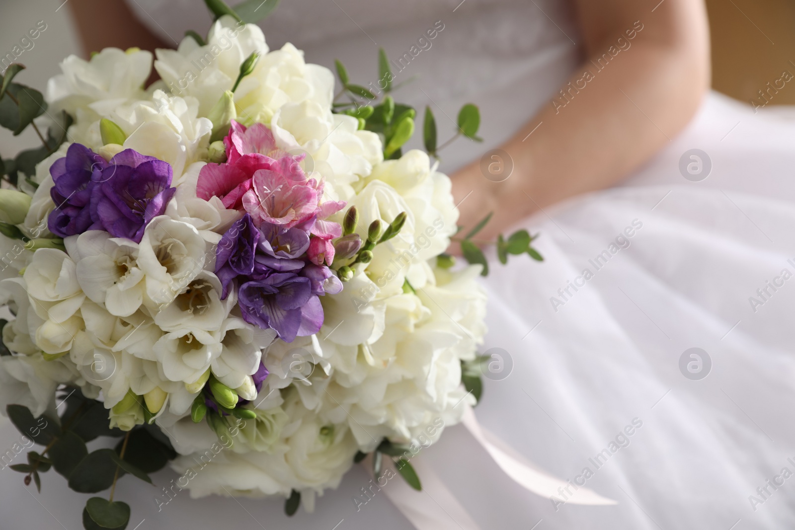 Photo of Bride holding beautiful bouquet with spring freesia flowers, closeup