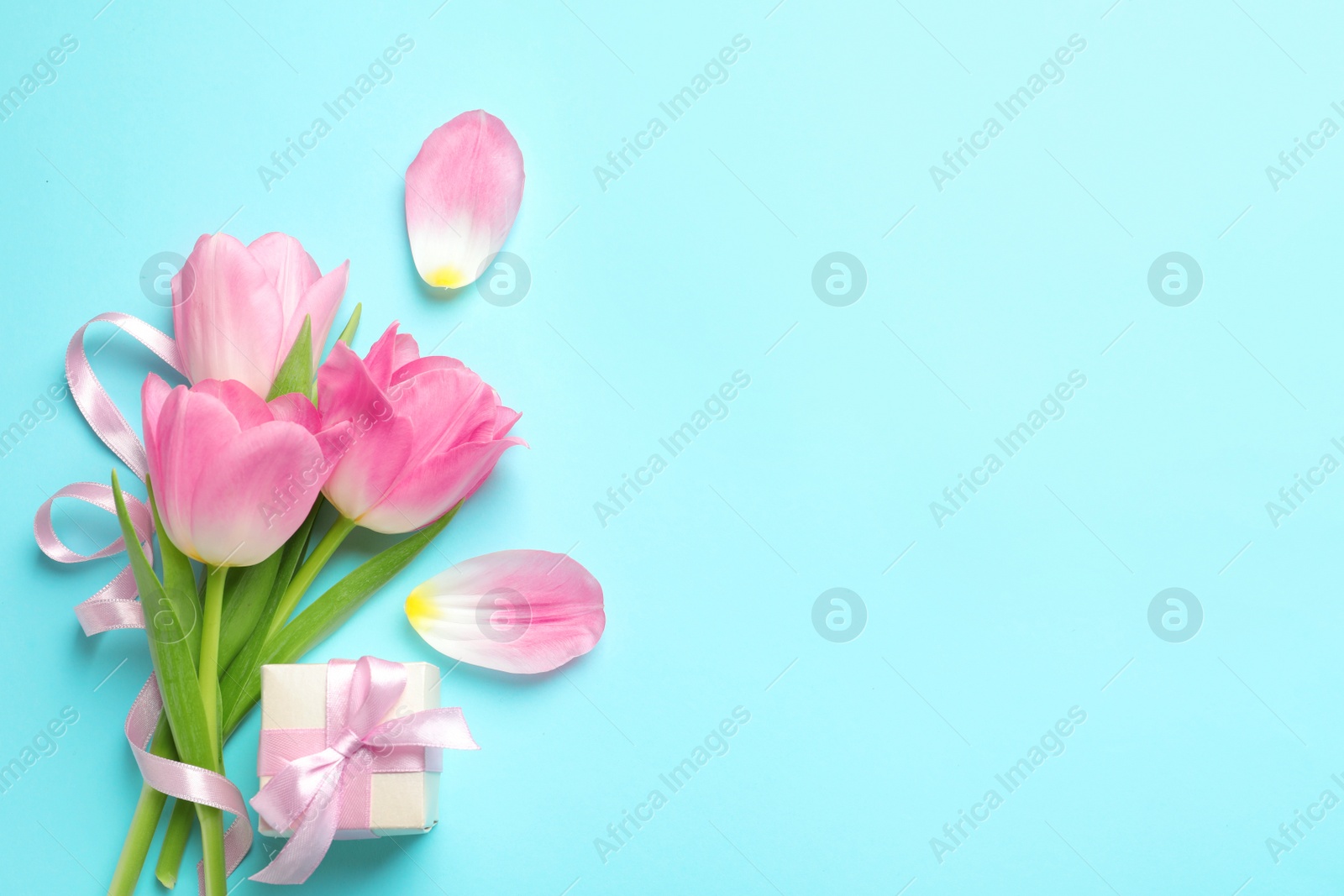 Photo of Flat lay composition of tulips on blue background, space for text. International Women's Day