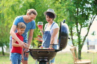 Photo of Happy family having barbecue with modern grill outdoors