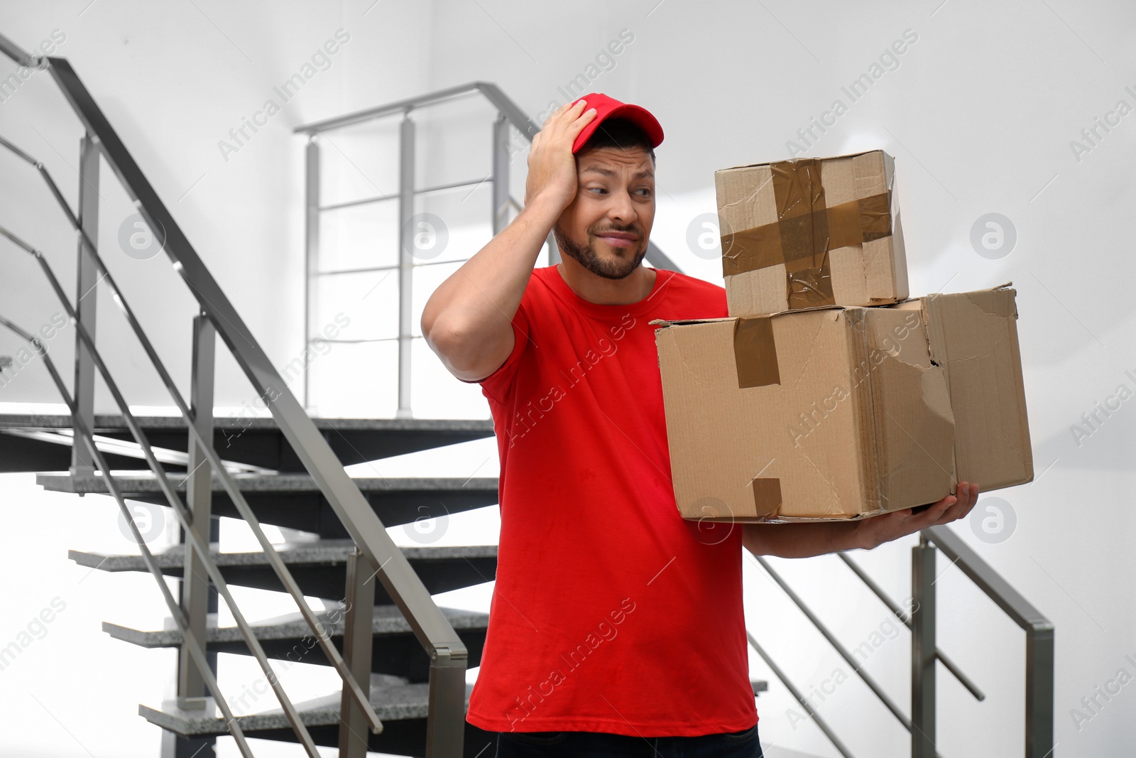Photo of Emotional courier with damaged cardboard boxes indoors. Poor quality delivery service