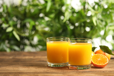 Photo of Glasses of fresh tangerine juice and fruits on wooden table