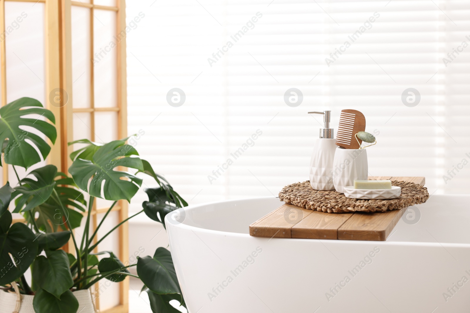 Photo of Different personal care products and accessories on bath tub in bathroom