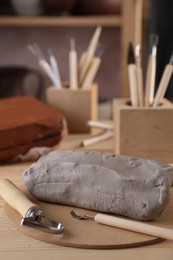 Clay and set of modeling tools on wooden table in workshop