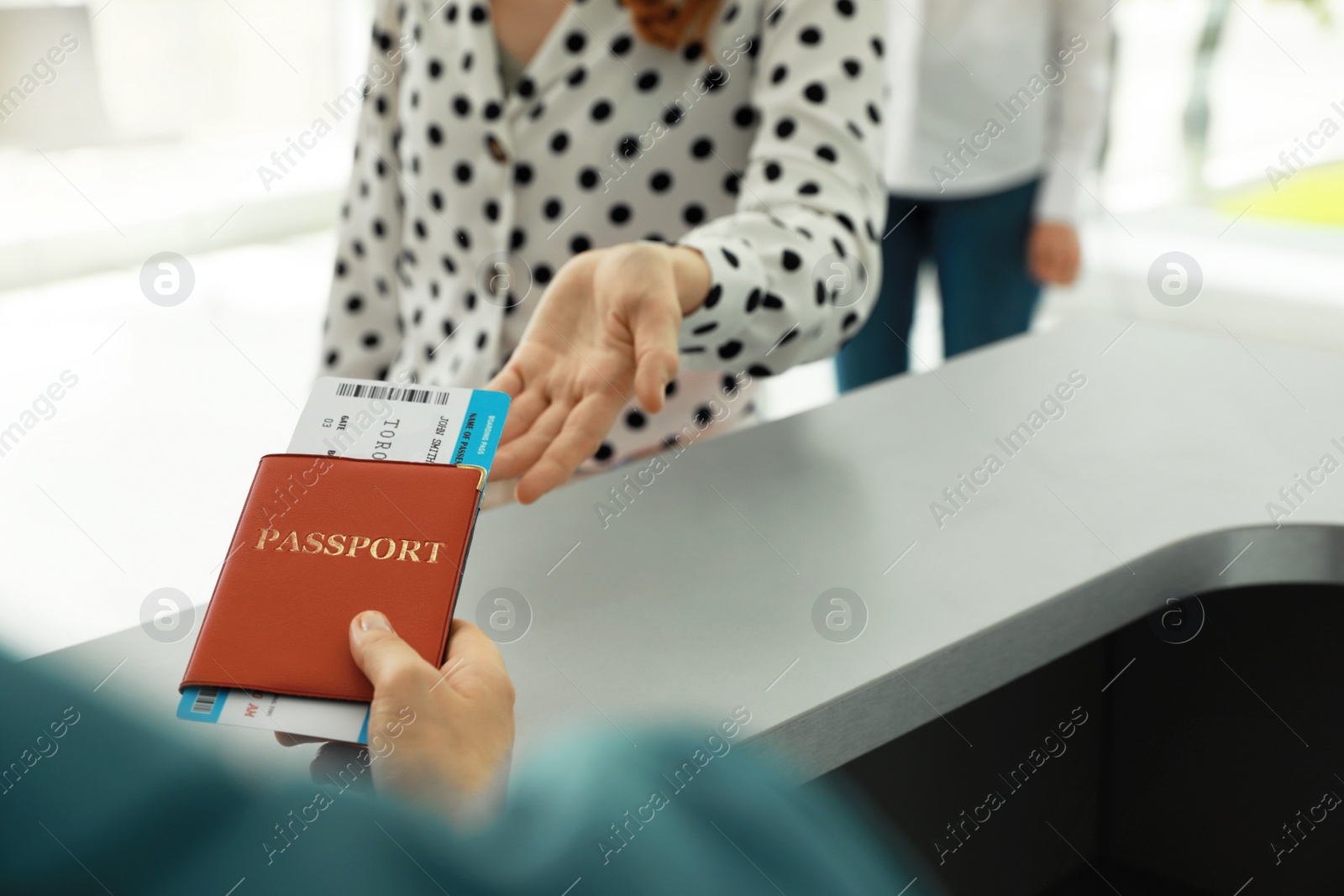 Photo of Agent giving passport and ticket to woman at check-in desk in airport, closeup