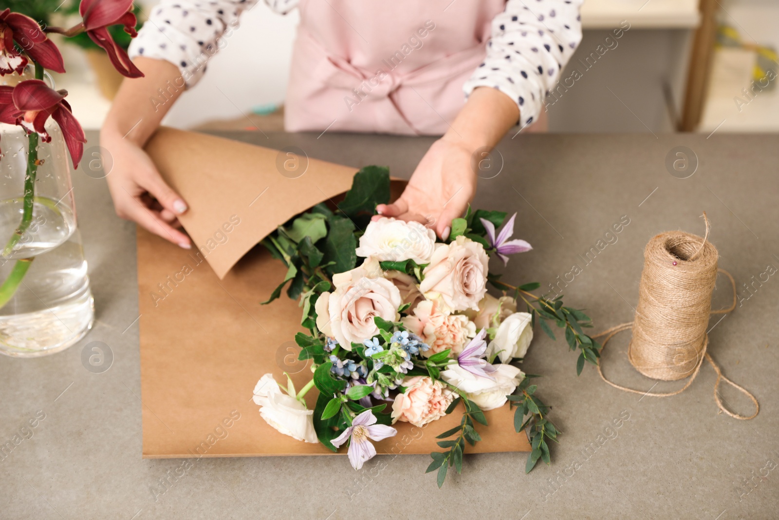 Photo of Florist making bouquet with fresh flowers at table, closeup