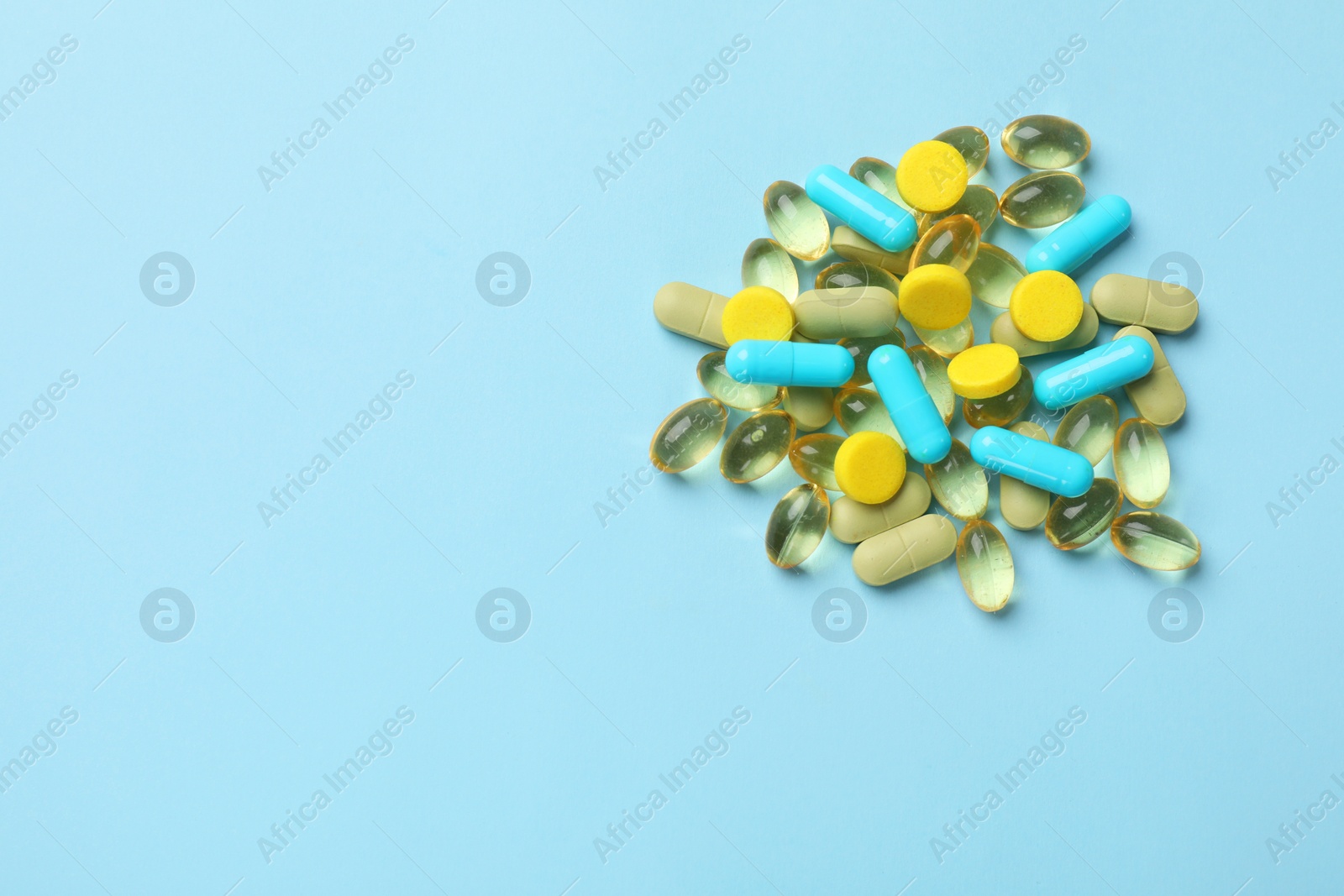 Photo of Different vitamin pills on light blue background, top view. Space for text