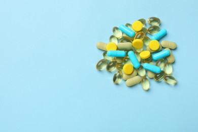 Photo of Different vitamin pills on light blue background, top view. Space for text