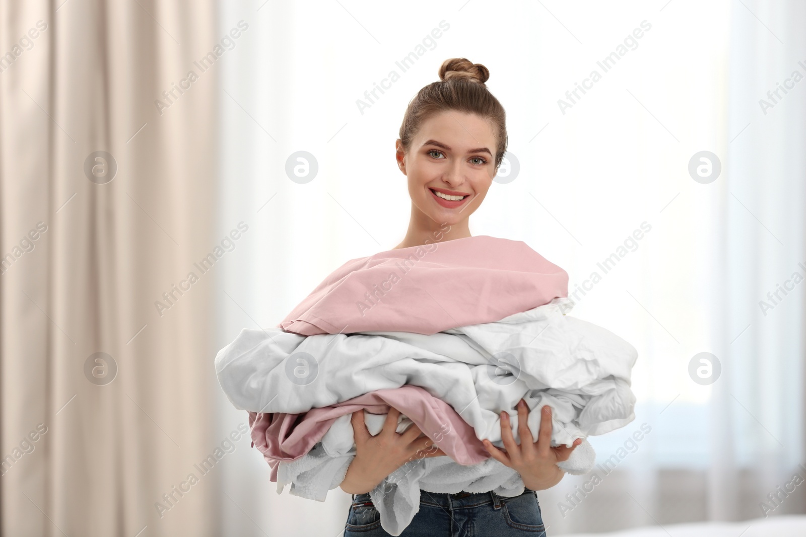 Photo of Woman holding pile of dirty laundry indoors