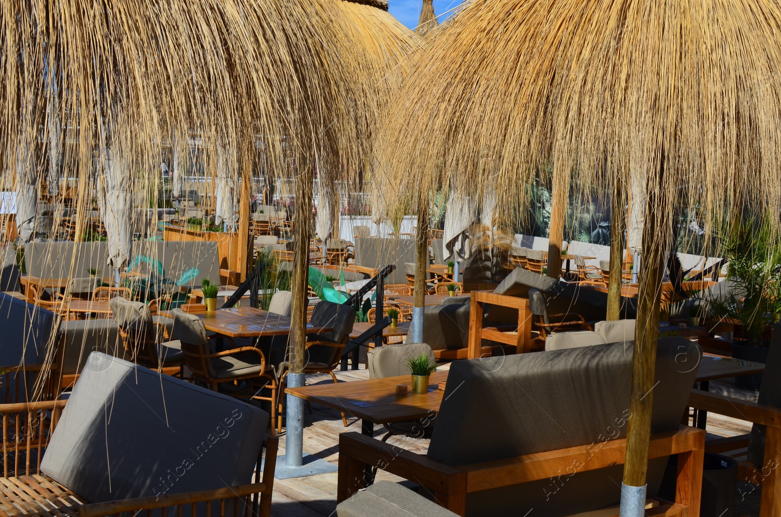 Photo of Beautiful straw beach umbrellas in modern outdoors cafe