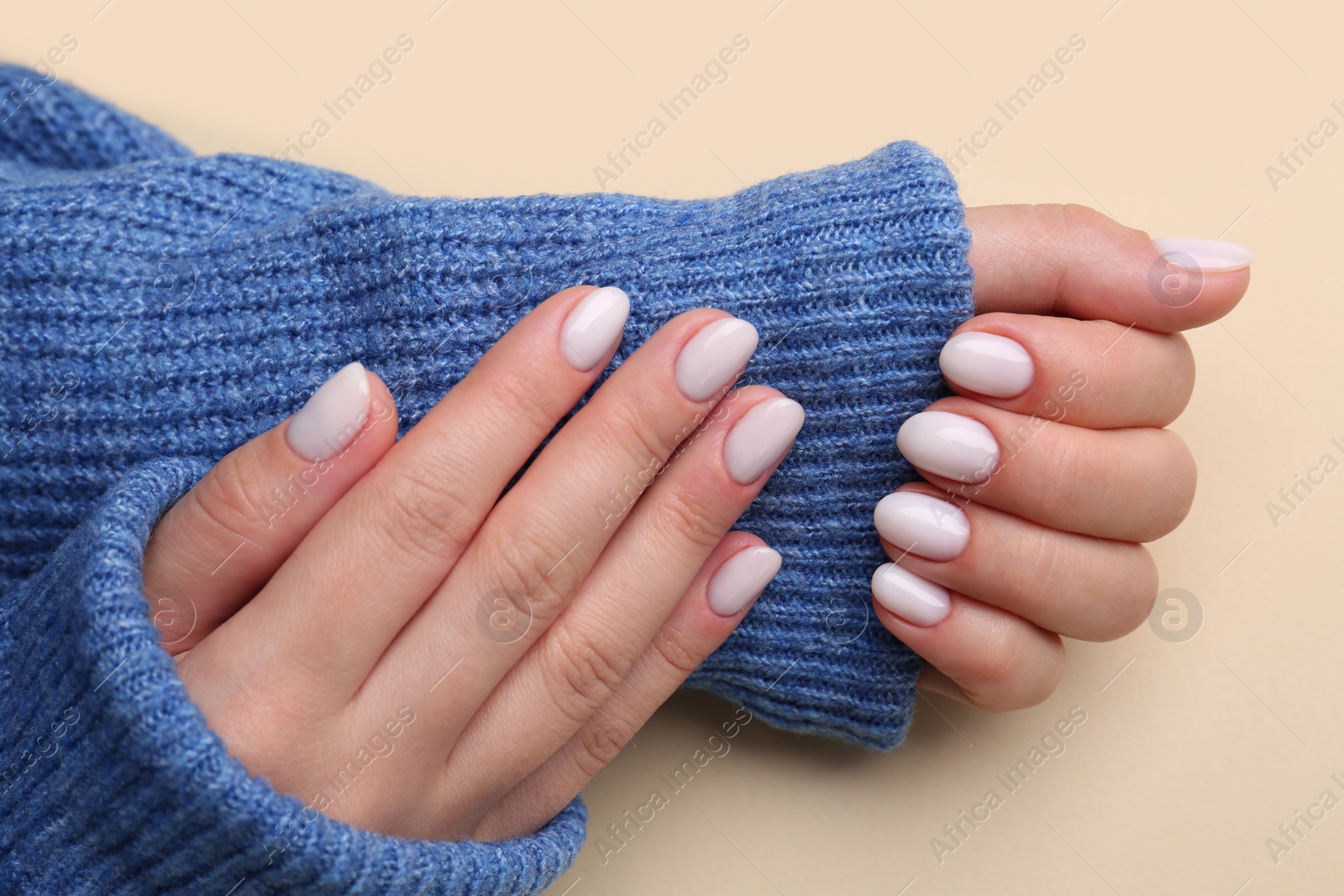 Photo of Woman showing her manicured hands with white nail polish on beige background, closeup