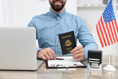 Photo of Immigration to United States of America. Smiling embassy worker with passport and documents at wooden table in office, closeup