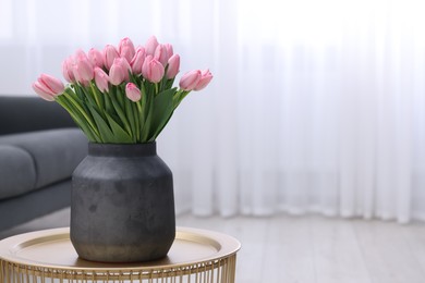 Photo of Bouquet of beautiful pink tulips in vase on table indoors, space for text