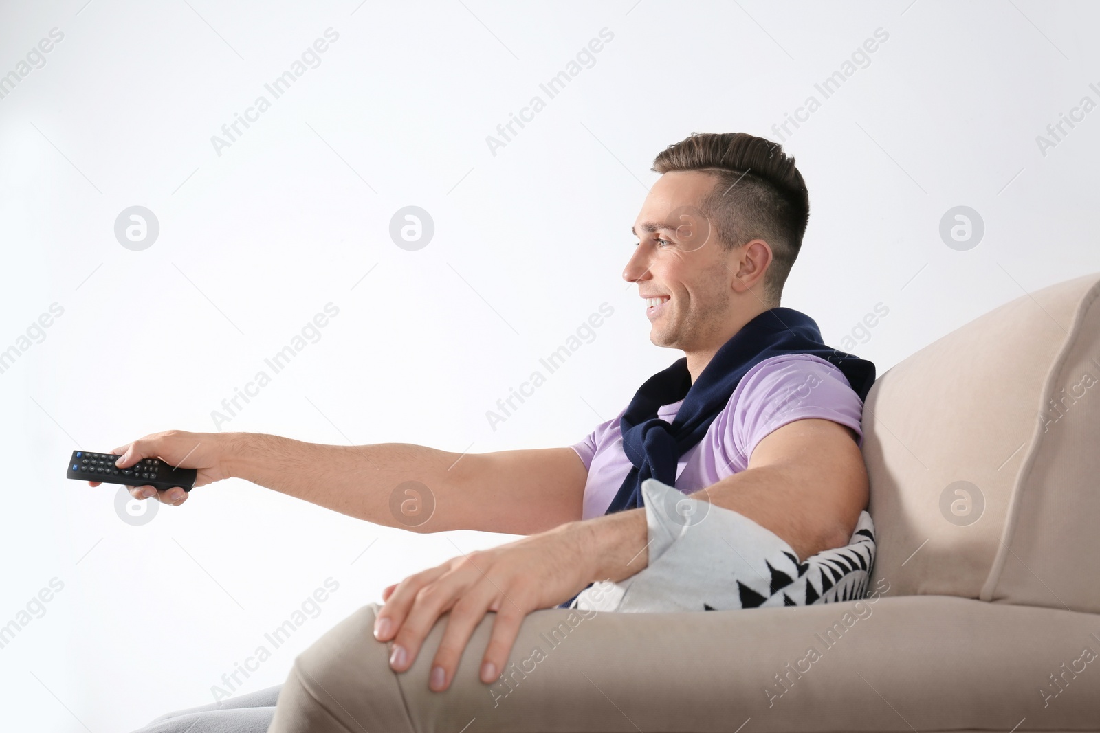 Photo of Handsome young man watching TV on sofa against white background