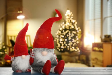 Image of Funny Christmas gnomes on blue wooden table in room with festive decorations. Space for text