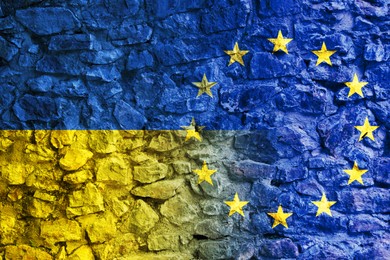 Flags of Ukraine and European Union on stone wall. International diplomatic relationships