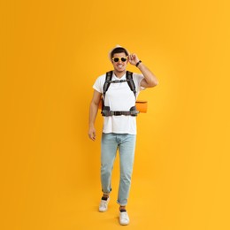 Male tourist with travel backpack on yellow background