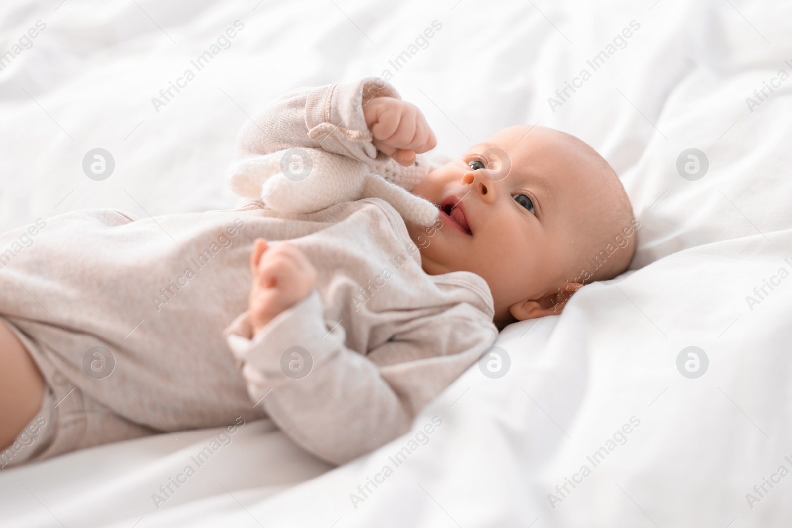 Photo of Cute little baby lying on white sheets