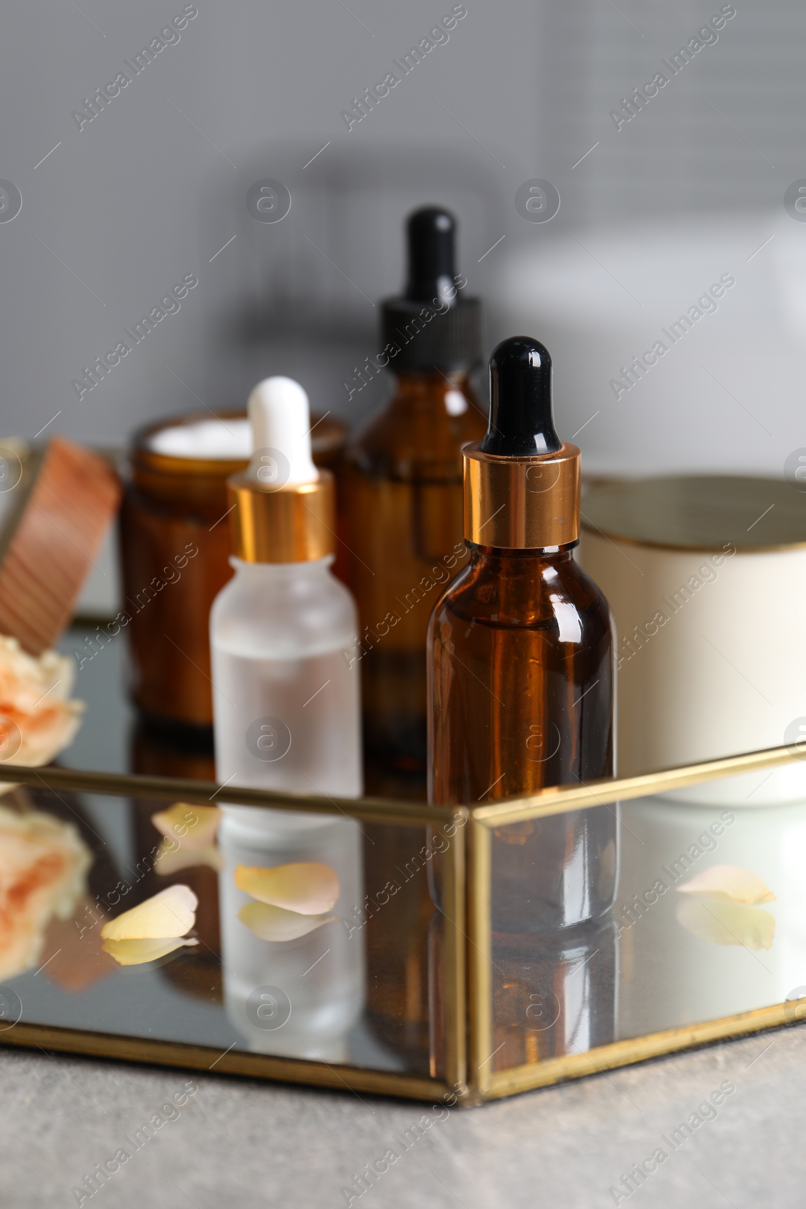 Photo of Bottles of cosmetic serum and beauty products on gray table, closeup