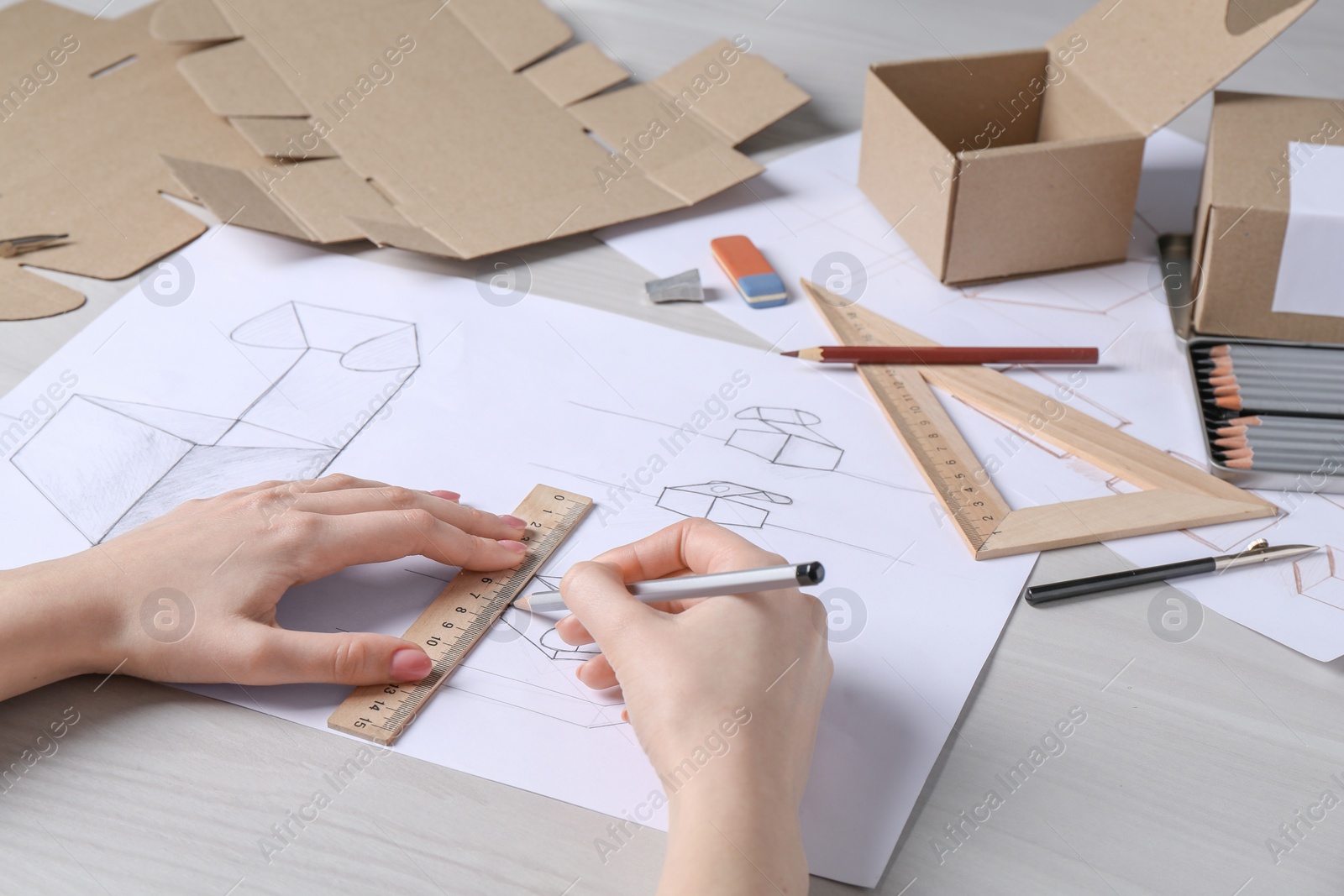 Photo of Woman creating packaging design at light wooden table, closeup