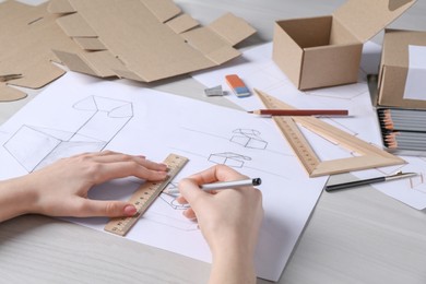 Photo of Woman creating packaging design at light wooden table, closeup